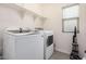 Well-lit laundry room with full size washer and dryer, floating shelves and tile floor at 4044 S 58Th Ln, Phoenix, AZ 85043