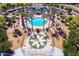 Aerial view of a community pool area with a circular pool, lounge chairs, a playground, and palm trees at 44158 W Canyon Creek Dr, Maricopa, AZ 85139