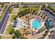 Aerial view of a community pool area with lounge chairs, a playground, picnic tables, and palm trees at 44158 W Canyon Creek Dr, Maricopa, AZ 85139
