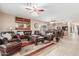 Spacious living room featuring leather furniture, ceiling fan, neutral paint, and an open floor plan to the kitchen at 44158 W Canyon Creek Dr, Maricopa, AZ 85139