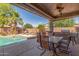 Covered patio featuring an outdoor kitchen with a grill and seating area with a pool in the background at 44158 W Canyon Creek Dr, Maricopa, AZ 85139