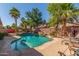 Backyard oasis showcasing a freeform pool, rock waterfall, and desert landscaping, creating a serene retreat at 44158 W Canyon Creek Dr, Maricopa, AZ 85139