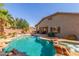 Inviting backyard pool and spa with lush landscaping, outdoor seating, and a covered patio at 44158 W Canyon Creek Dr, Maricopa, AZ 85139