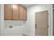 Bright laundry room with wood cabinets, white walls and baseboards, and a gray door at 5103 E Juniper Ave, Scottsdale, AZ 85254