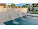 Swimming pool with three water features, stone landscaping, lush green grass, and tasteful wall decor at 5103 E Juniper Ave, Scottsdale, AZ 85254
