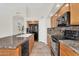 Well-lit kitchen with granite countertops, wooden cabinets, and black appliances provides a functional cooking space at 7464 E Lompoc Ave, Mesa, AZ 85209