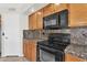 The well-appointed kitchen features ample wooden cabinetry, granite countertops and modern black appliances at 7464 E Lompoc Ave, Mesa, AZ 85209