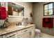 Neutral toned bathroom featuring granite counters, a decorative mirror, and a bright, natural lit window at 7753 E Whisper Rock Trl, Scottsdale, AZ 85266