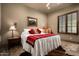 Bedroom with wood floors, shuttered windows, and a queen-sized bed, with a cozy western flair at 7753 E Whisper Rock Trl, Scottsdale, AZ 85266