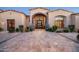 Elegant home featuring an arched entryway, wrought iron door, stone details, and manicured landscaping at 7753 E Whisper Rock Trl, Scottsdale, AZ 85266