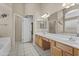 Bright bathroom featuring tile floors, double sink vanity, adjacent room, tub with shower at 12214 W Madison St, Avondale, AZ 85323