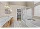 Bright bathroom featuring double sinks, a soaking tub, and glass-enclosed shower and vanity at 12214 W Madison St, Avondale, AZ 85323