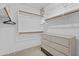 Organized walk-in closet with white shelves, wooden rods, and built-in storage for clothes at 12214 W Madison St, Avondale, AZ 85323