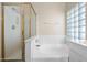 Bathroom with soaking tub and separate glass-enclosed shower, complemented by a glass block window at 13857 W Windsor Ave, Goodyear, AZ 85395