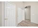 Hallway with light wood-style floors and neutral walls, featuring multiple white paneled doors and ample closet space at 13857 W Windsor Ave, Goodyear, AZ 85395