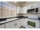 Close-up of a well-lit kitchen with white cabinets, an oven, a microwave, and black countertops at 13857 W Windsor Ave, Goodyear, AZ 85395