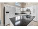 Modern kitchen with white cabinets, dark countertops, kitchen island, and stainless steel refrigerator at 13857 W Windsor Ave, Goodyear, AZ 85395