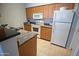 Functional kitchen featuring light wood cabinets, appliances, and a tile floor at 14250 W Wigwam Blvd # 522, Litchfield Park, AZ 85340