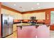 Kitchen features stainless steel appliances, breakfast bar, light wood cabinets, and terracotta accent wall at 16077 W Vale Dr, Goodyear, AZ 85395
