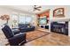 Bright living room with a large window view, black leather furniture, a fireplace, and a southwestern-style rug at 16077 W Vale Dr, Goodyear, AZ 85395