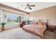 Tranquil main bedroom with large windows overlooking the front yard, carpet, ceiling fan, and bedside tables at 16077 W Vale Dr, Goodyear, AZ 85395
