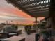 Beautiful sunset view from the covered patio featuring cozy seating and lovely desert landscaping at 16077 W Vale Dr, Goodyear, AZ 85395