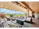 Inviting covered patio with wicker furniture and a cozy fireplace, perfect for outdoor gatherings and enjoying the golf course view at 16077 W Vale Dr, Goodyear, AZ 85395