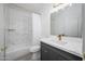 Modern bathroom with marble tile, bathtub, and vanity with gray cabinets and gold hardware at 17610 N 17Th Pl # 2, Phoenix, AZ 85022