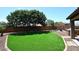 Expansive backyard features well-manicured artificial grass, mature trees, and a stone patio area, perfect for outdoor entertaining at 18351 W Southgate Ave, Goodyear, AZ 85338