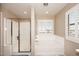 Bright bathroom with a glass shower, soaking tub, and white plantation shutters at 18351 W Southgate Ave, Goodyear, AZ 85338