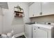 Bright laundry room boasts modern washer/dryer units, hexagon tile flooring, and stylish shelving at 1910 W Desert Hollow Dr, Phoenix, AZ 85085