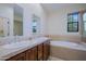 Bright bathroom featuring double sinks, warm wood cabinetry, and a relaxing soaking tub with a window at 20750 N 87Th St # 2115, Scottsdale, AZ 85255