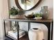 Decorated console table featuring a round mirror, plants, vases, and books at 2150 E Bell Rd # 1068, Phoenix, AZ 85022