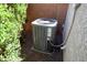 A close-up view of the property's air conditioner unit next to a brick wall and bush at 21883 N 263Rd Dr, Buckeye, AZ 85396