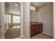 Bathroom vanity with wood cabinets and view to the living room with carpet at 21883 N 263Rd Dr, Buckeye, AZ 85396