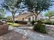 View of the home's exterior, featuring desert landscaping, brick fencing, and mature trees at 2201 N Comanche Dr # 1093, Chandler, AZ 85224