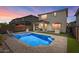 Twilight view of the backyard featuring a sparkling pool, covered patio area with lounge seating, and outdoor kitchen at 22136 N 28Th Pl, Phoenix, AZ 85050