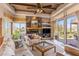 Open living room with a stone fireplace, wood beam ceilings, and sliding glass doors to the patio at 23760 N 80Th Way, Scottsdale, AZ 85255