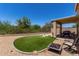 Enjoyable backyard featuring an artificial grass area, fire pit, and covered patio for entertaining at 27420 N 63Rd Dr, Phoenix, AZ 85083