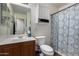 Clean bathroom featuring wood cabinets, a sink, a toilet, a cabinet for linens, and a floral shower curtain at 27420 N 63Rd Dr, Phoenix, AZ 85083