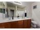 Well-lit bathroom featuring a double sink vanity, large mirror, and modern fixtures at 27420 N 63Rd Dr, Phoenix, AZ 85083