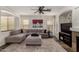 Comfortable living room featuring a cozy gray sectional couch, ceiling fan and stone tile floor at 27420 N 63Rd Dr, Phoenix, AZ 85083