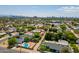 An aerial view shows homes with pools and green trees in a quiet suburban neighborhood with a city in the background at 3115 N 26Th St, Phoenix, AZ 85016