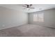 Spacious carpeted bedroom with a ceiling fan and natural light from a large window at 316 N 78Th Pl, Mesa, AZ 85207