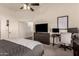 Bright main bedroom with a modern fan, TV, workspace, and neutral decor at 43803 W Wade Dr, Maricopa, AZ 85138