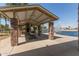 Stone pavilion with picnic tables and a BBQ grill overlooking a lake with water features at 43803 W Wade Dr, Maricopa, AZ 85138