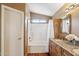Bright bathroom features a bathtub, wood vanity with stone countertop, and a light colored tiled floor at 4430 E Creosote Dr, Cave Creek, AZ 85331