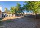 Spacious backyard with gravel, a covered patio, mature trees, and perimeter walls at 5529 W Villa Maria Dr, Glendale, AZ 85308