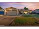 Charming single-story home featuring a two-car garage, well-manicured lawn, and inviting front porch at sunset at 5529 W Villa Maria Dr, Glendale, AZ 85308