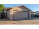Close-up of the two-car garage with a spacious driveway and desert landscaping in the front yard at 5529 W Villa Maria Dr, Glendale, AZ 85308